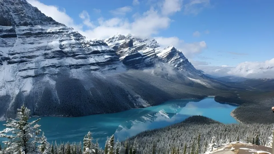 Il tranquillo lago turchese davanti a montagne innevate e foreste di sempreverdi vicino alla École Secondaire Augustin-Norbert-Morin.