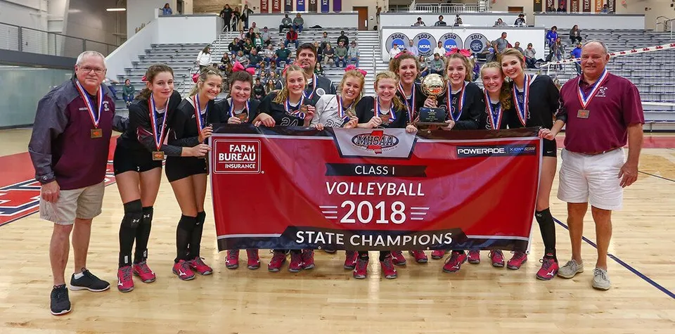 La squadra di pallavolo della Our Lady Academy posa con medaglie, un trofeo e uno striscione del campionato statale 2018.
