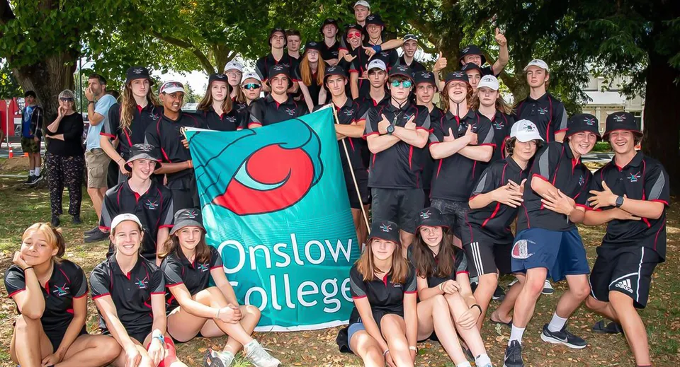 Un gruppo di studenti dell'Onslow College all'aperto che tiene in mano una bandiera con il nome della scuola.