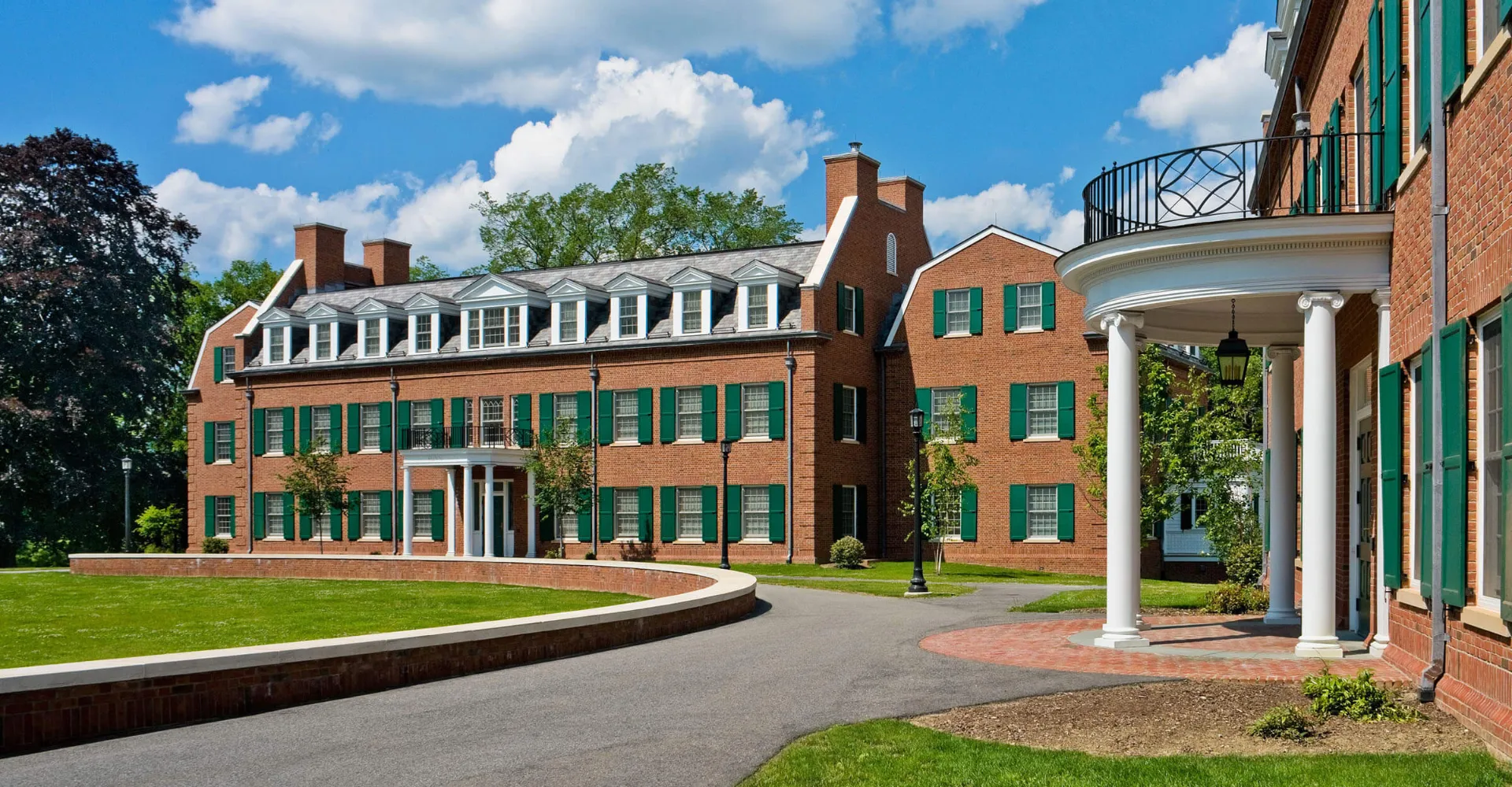 L'edificio in mattoni con portico a colonne nel campus della The Hotchkiss School si trova su un prato curato sotto un cielo blu.