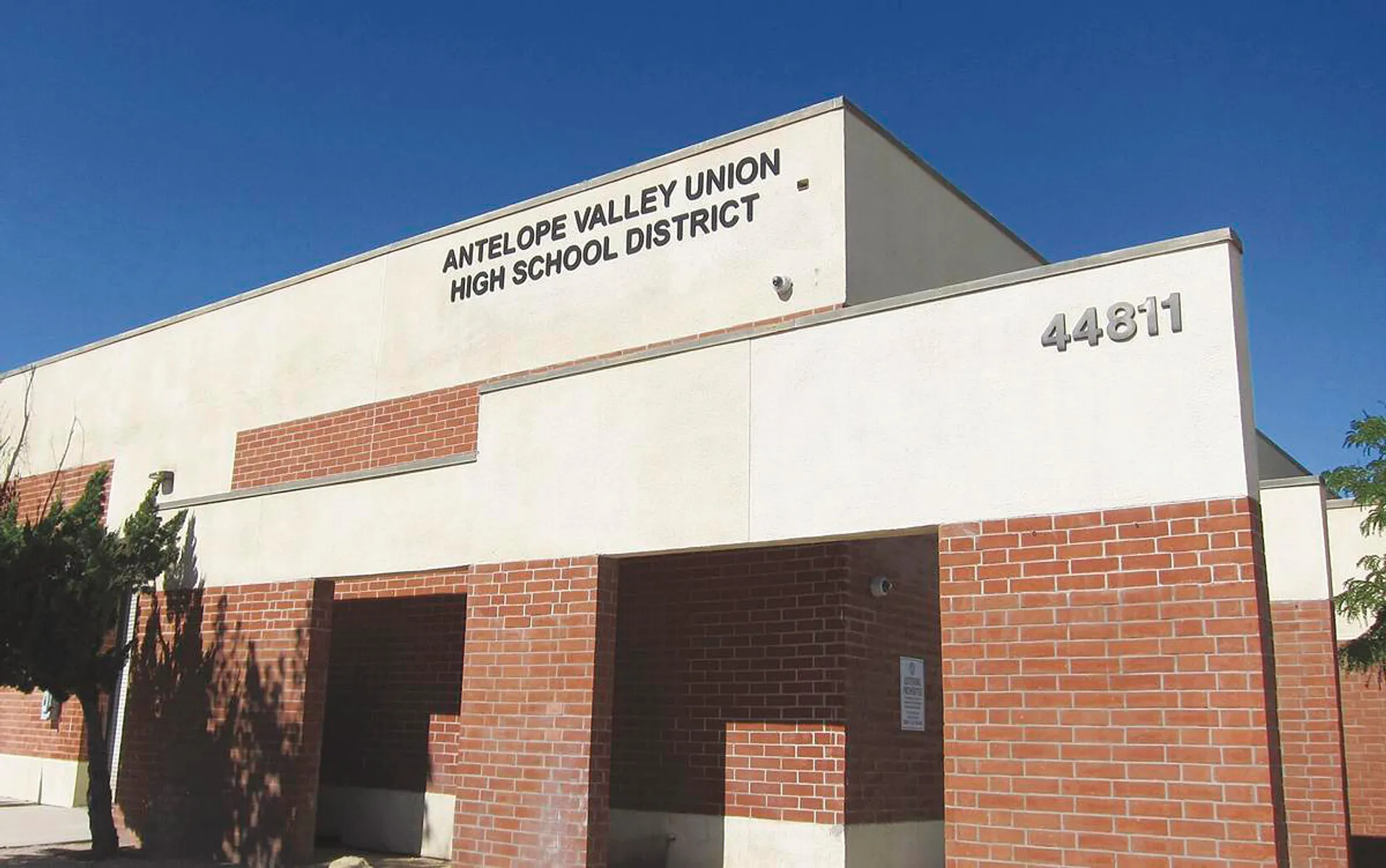 L'edificio grande dell'Antelope Valley Union High School District in mattoni e cemento davanti a un cielo azzurro e limpido.