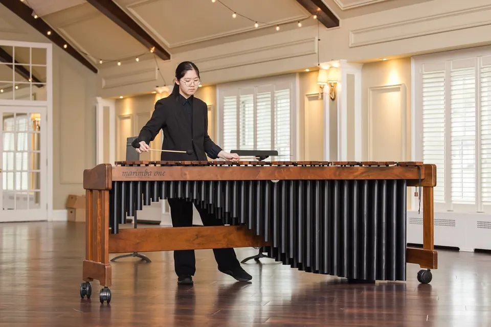 Una persona suona una grande marimba di legno in un elegante ambiente della Elite Preparatory Academy.