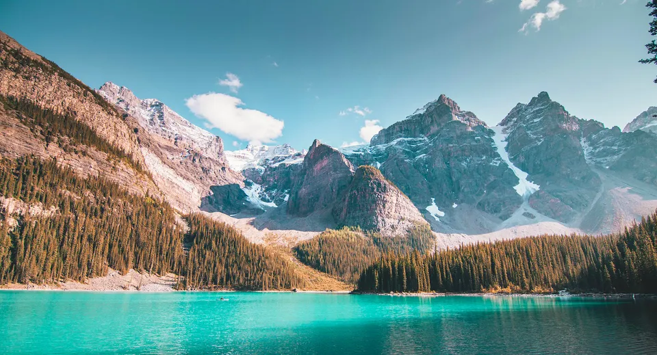 Un lago alpino con montagne innevate e un bosco in primo piano vicino alla James Fowler High School.