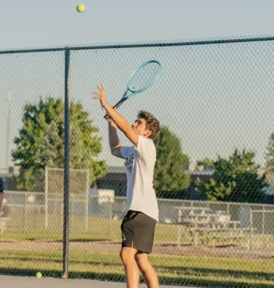 Schüler beim Aufschlag auf einem Tennisplatz