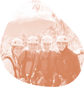 Cuatro estudiantes con casco de esquí posando en la montaña