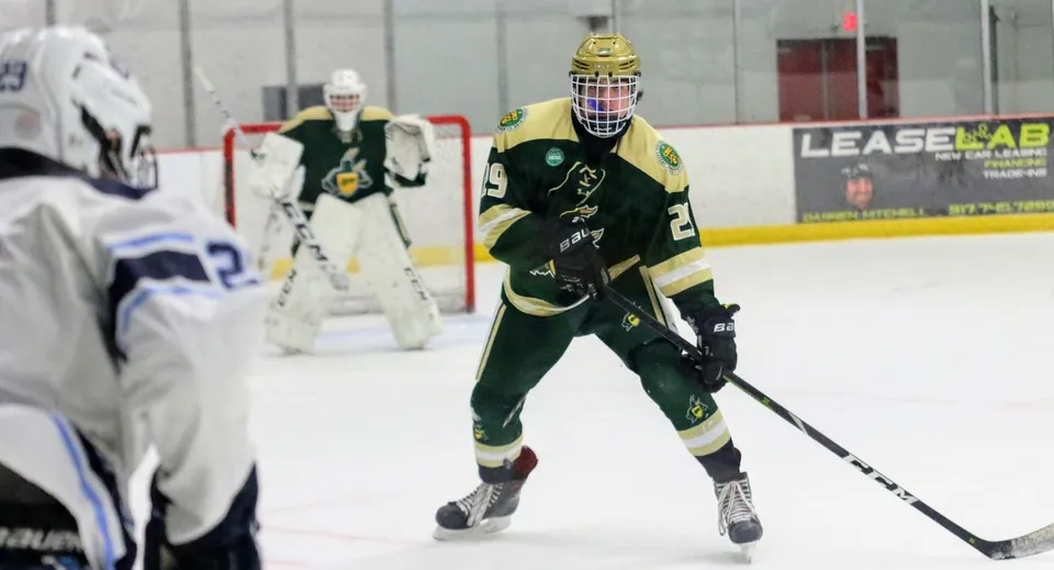 Un giocatore di hockey della St. John’s-Ravenscourt School è sul ghiaccio con maglia verde e casco.