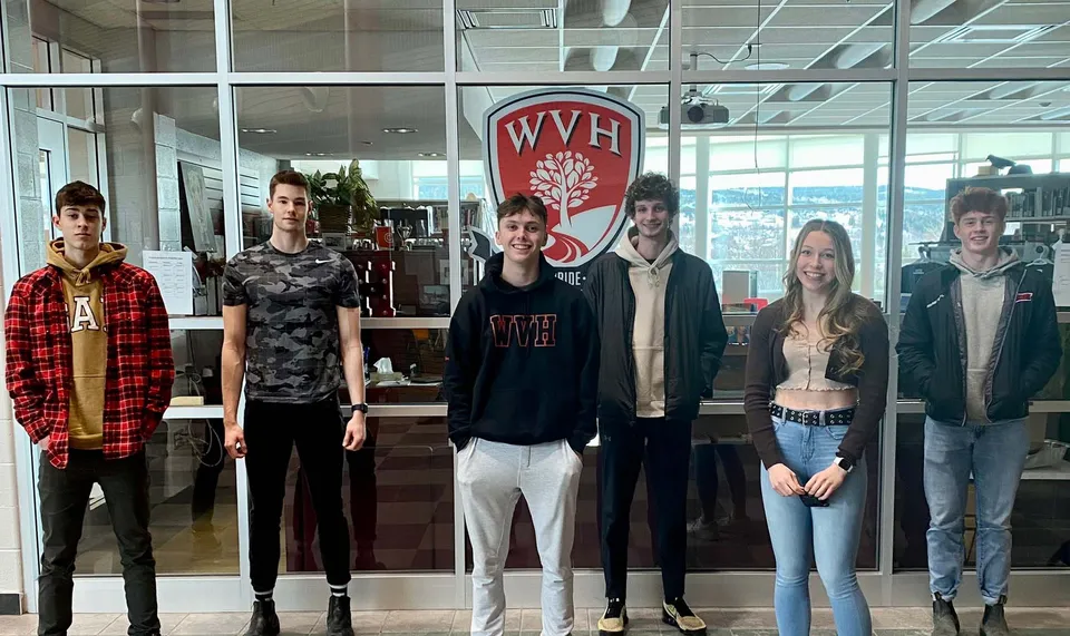Un gruppo di studenti si trova davanti al grande logo WVH all'interno dell'edificio della Waterford Valley High School.