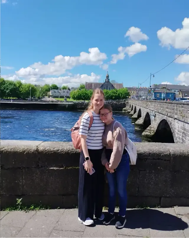 Due amiche si abbracciano su un ponte di pietra sopra un fiume, in Irlanda