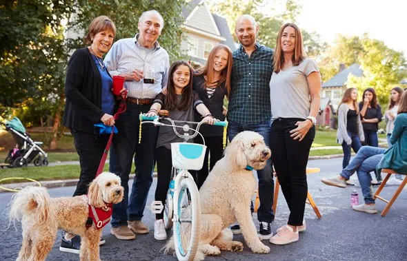Familia sonriente junto a sus dos perros y una bicicleta en una calle residencial
