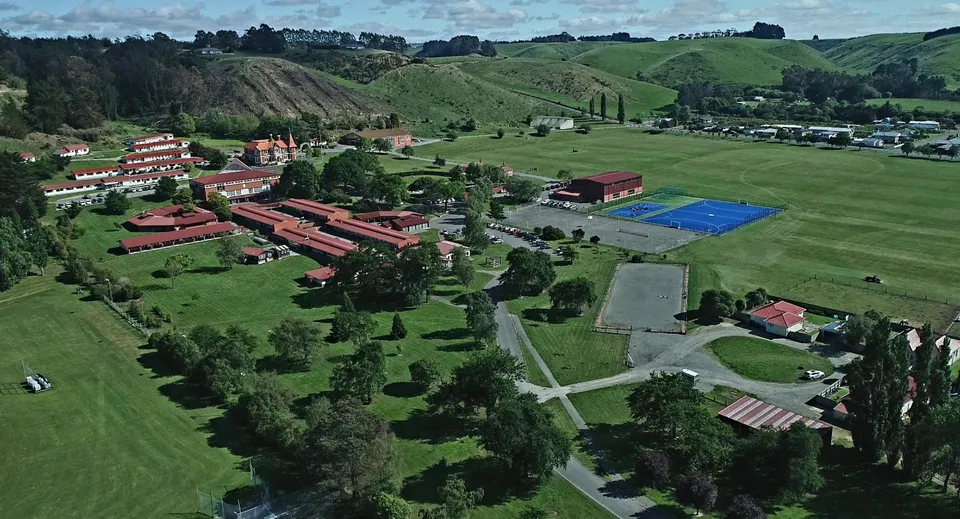 Il campo da tennis nel campus del St. Kevin’s College è circondato da colline verdi e edifici rossi.