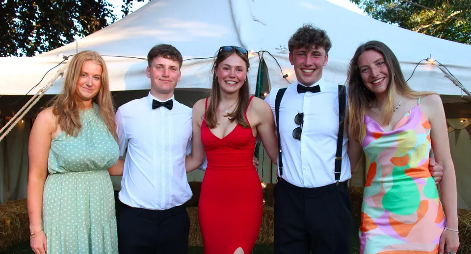 Un gruppo di cinque studenti della Hereford Cathedral School si trova davanti a una tenda all'aperto con alberi sullo sfondo.