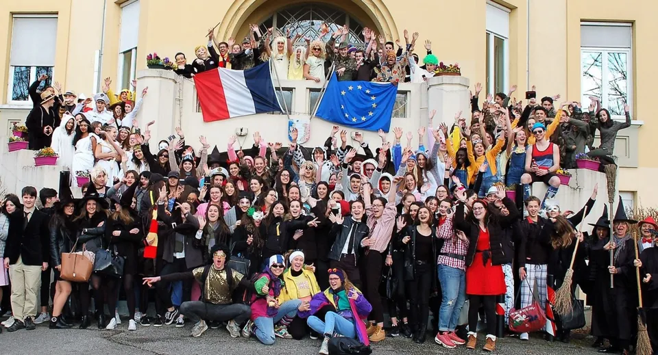 Un gruppo di studenti davanti al Lycée Polyvalent Philippine Duschenes mostra bandiere polacche e dell'UE davanti a un edificio con arco.