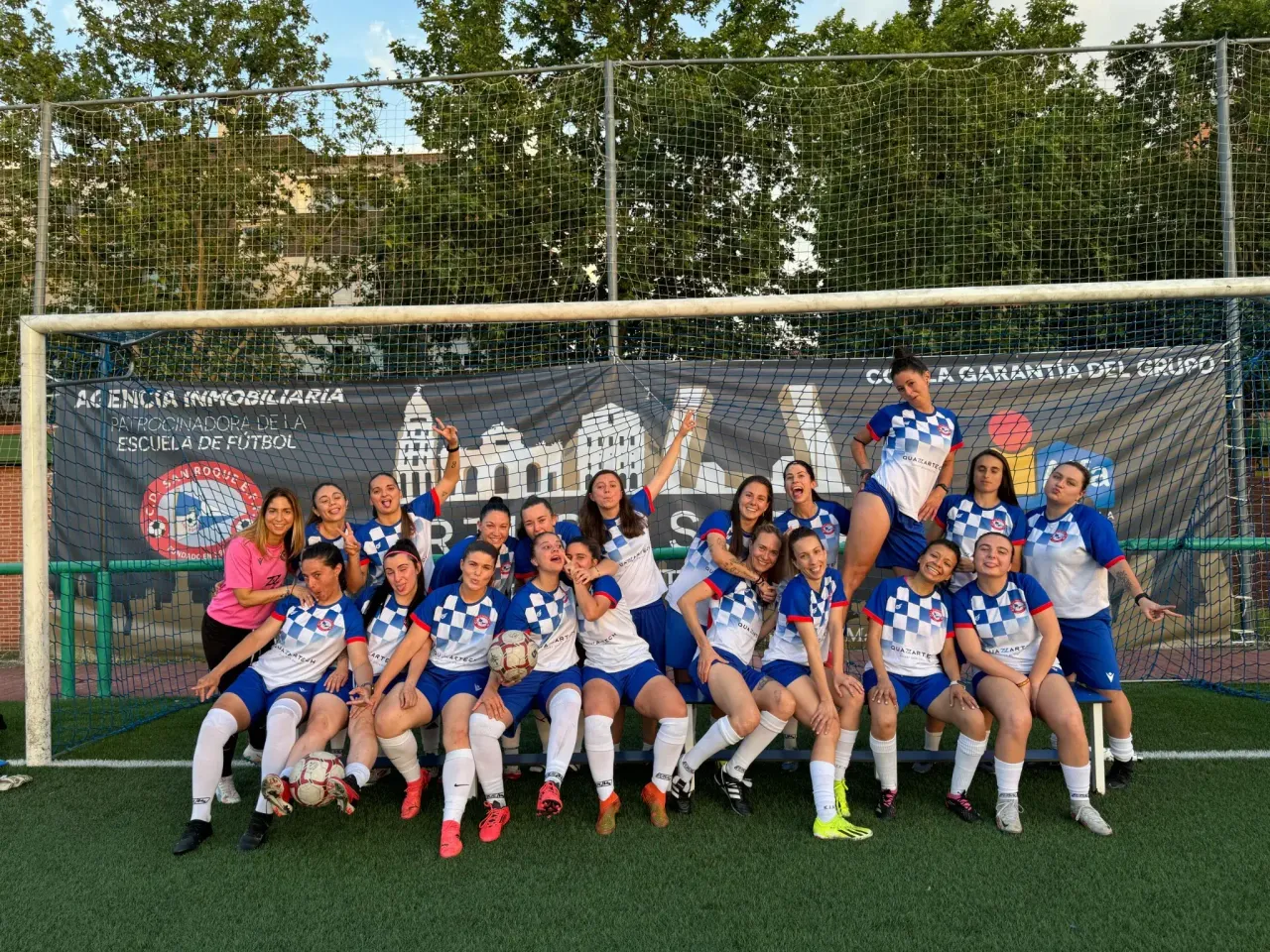 Squadra di calcio femminile in posa davanti alla porta del campo di una scuola calcio spagnola
