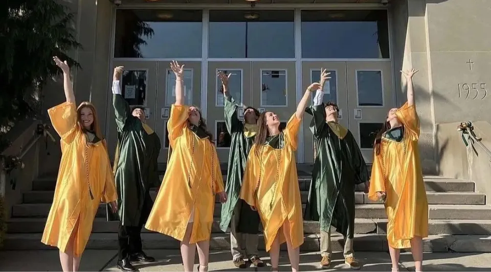Studenti della Nativity BVM High School sono sulle scale in abiti colorati e alzano le braccia all'unisono.