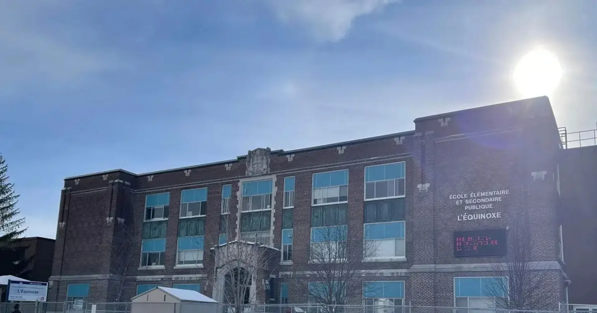 L'edificio in mattoni a più piani della École élémentaire et secondaire publique L'Équinoxe con grandi finestre sotto un cielo blu.