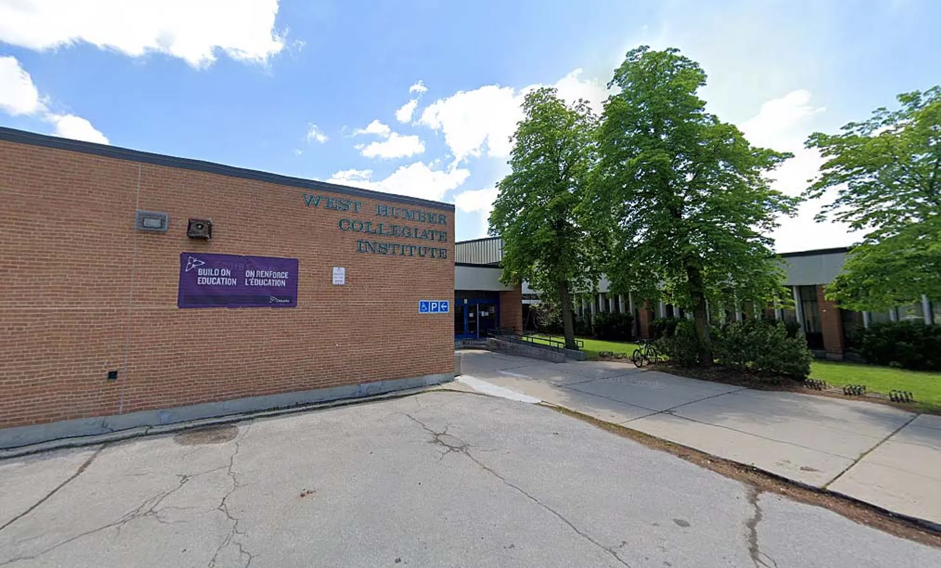 L'edificio in mattoni del West Humber Collegiate Institute è circondato da alberi e si trova lungo un viale lastricato.