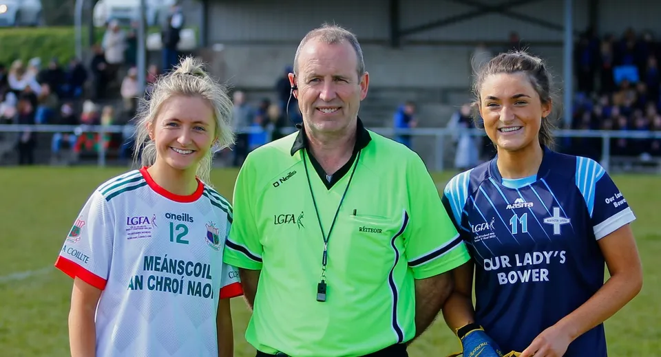 Un'atleta della Our Lady's Bower Secondary School sorride insieme a un arbitro e a un'avversaria sul campo da gioco.