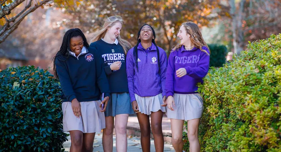 Quattro studentesse della Darlington School si trovano insieme all'aperto davanti ad alberi e fogliame.