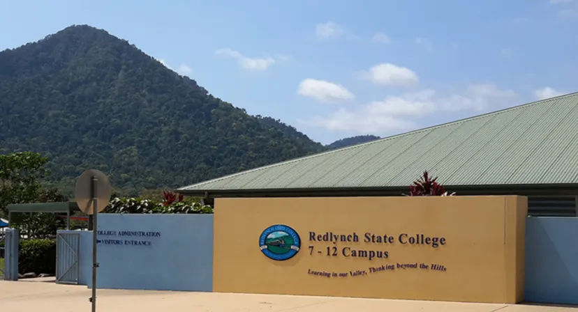 L'edificio giallo con il logo del Redlynch State College davanti a un paesaggio montuoso.