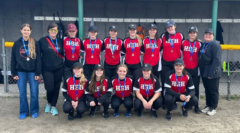 Un gruppo di studenti e studentesse in maglia rossa con la scritta HSH si trova sul campo sportivo della Holy Spirit High School.