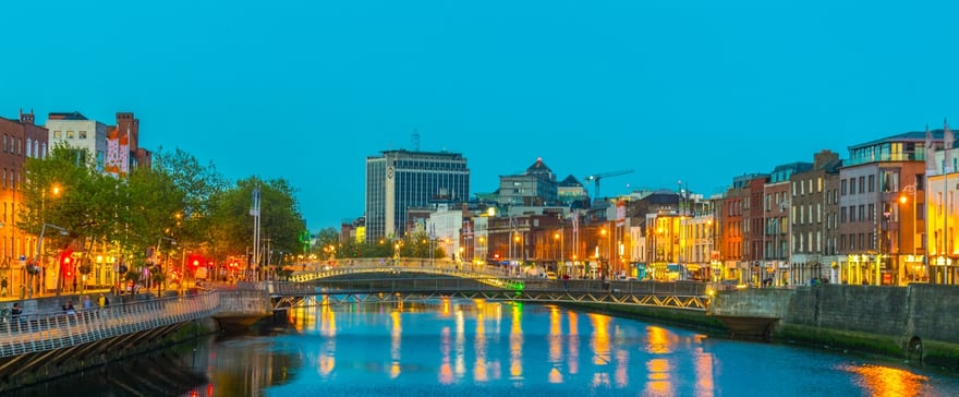 Il fiume Liffey a Dublino all'imbrunire con i palazzi illuminati e il ponte pedonale