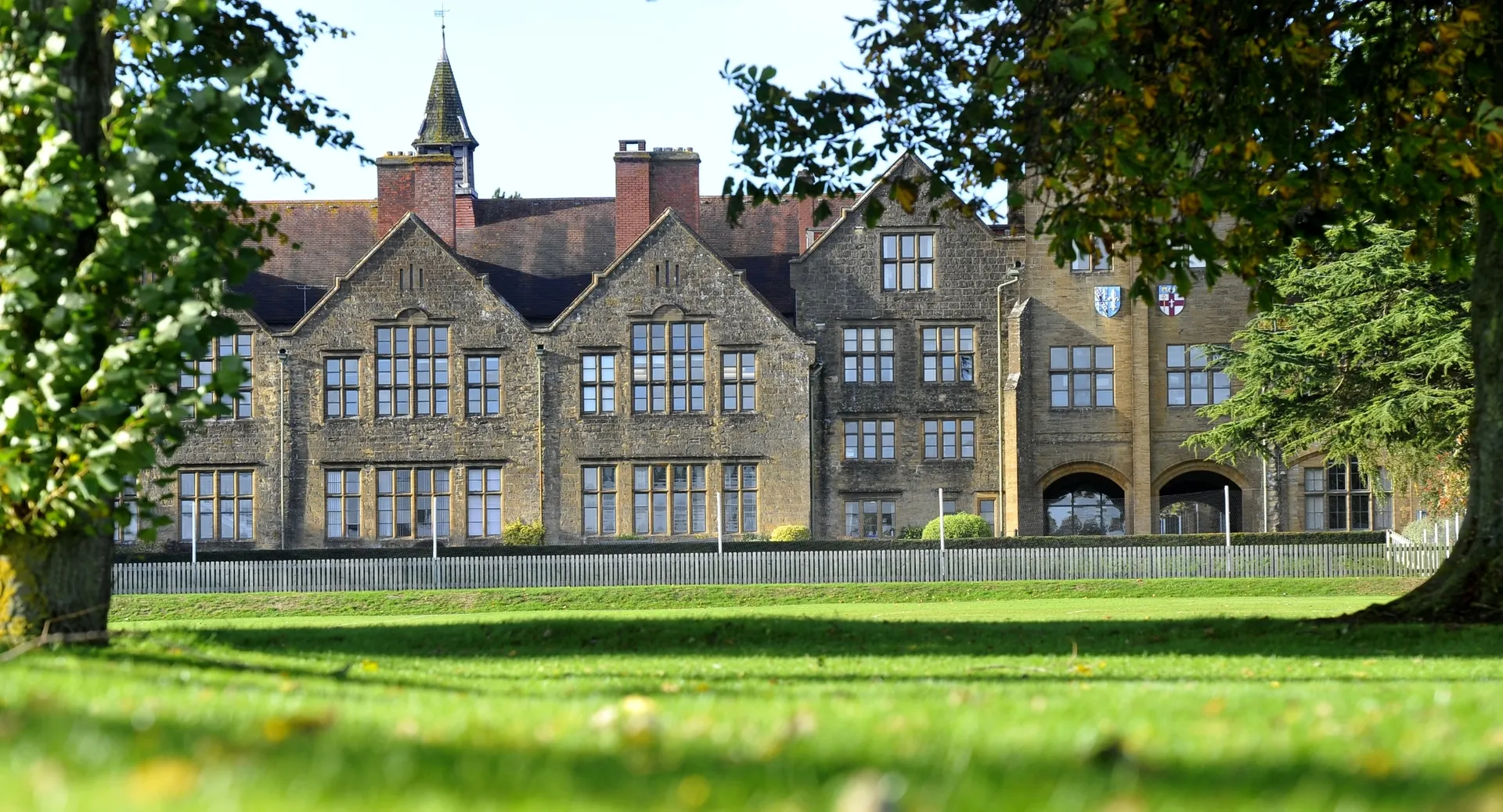 L'edificio principale storico della Sherborne Girls' School con un'alta torre e curati spazi verdi tutt'intorno.