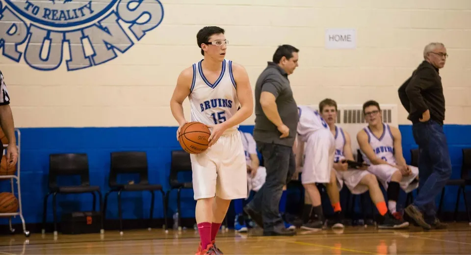 Un giocatore di pallacanestro in maglia blu sta con la palla sul campo da basket della Sugarloaf Senior High.