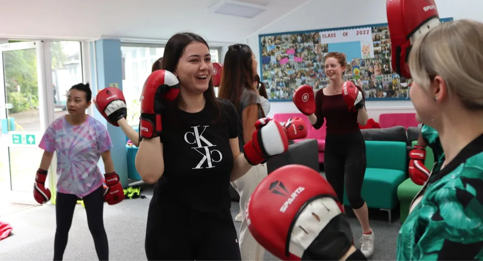 Le studentesse della Truro High School for Girls si allenano insieme con guantoni da boxe e caschi protettivi nella sala allenamento.