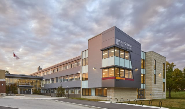 L'edificio moderno a più piani con facciate in vetro e cemento della M.M. Robinson High School sotto un cielo nuvoloso.