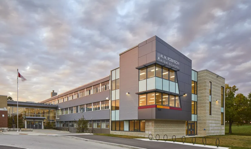 L'edificio moderno a più piani con facciate in vetro e cemento della M.M. Robinson High School sotto un cielo nuvoloso.