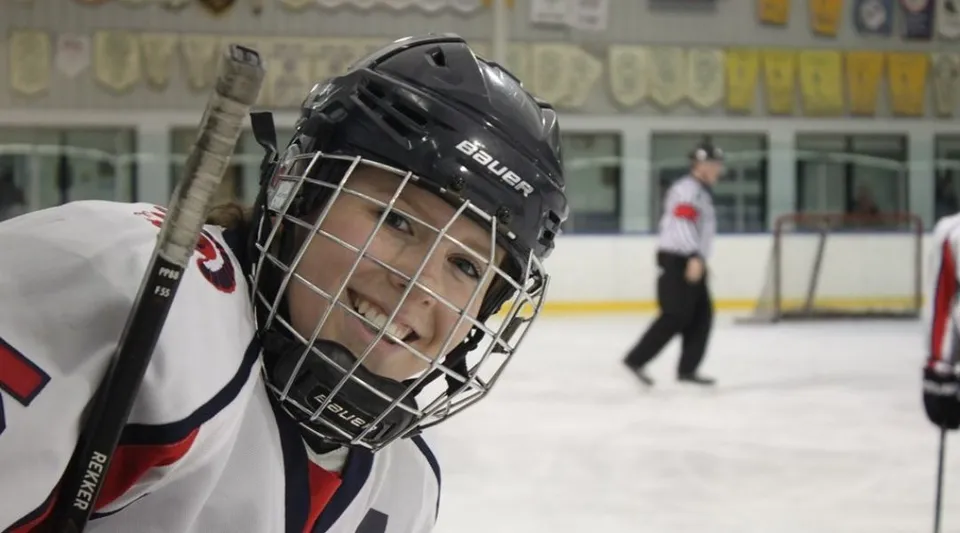 Un giovane giocatore di hockey si trova sulla pista di ghiaccio della Shaftesbury High con attrezzatura protettiva e casco nero.