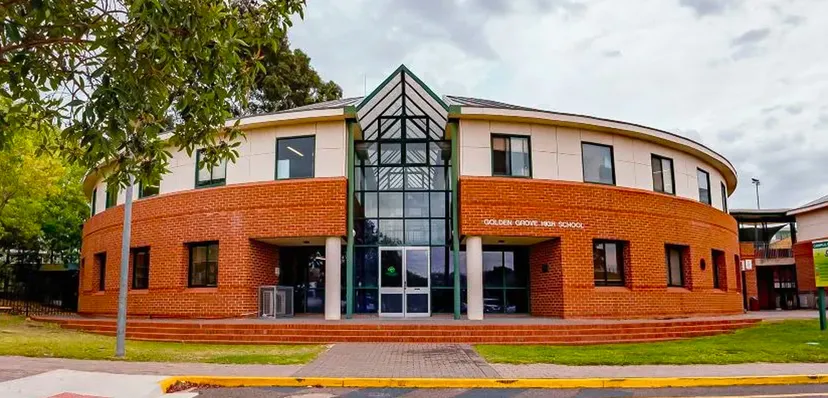 L'edificio principale moderno della Golden Grove High School con una struttura triangolare in vetro all'ingresso e dintorni verdi.