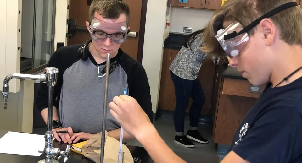 Due studenti della Fleetwood Park Secondary School esaminano un dispositivo nel laboratorio dell'officina.