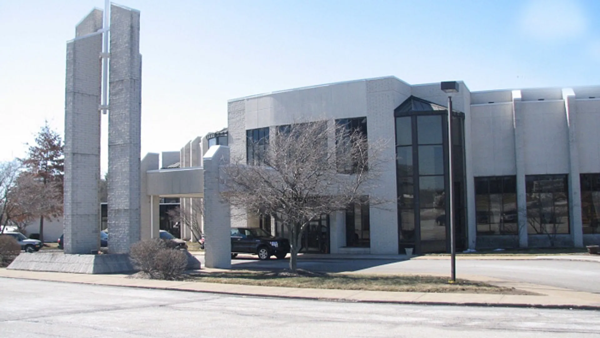 L'edificio moderno a più piani della Erie First Christian Academy si erge davanti ad alberi sotto un cielo azzurro e limpido.
