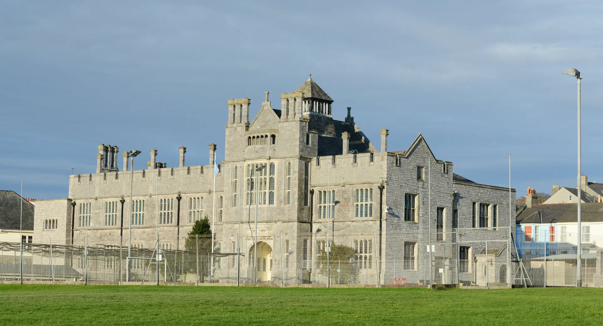 Un castello in stile medievale con torri sorge nel campus del Plymouth College di fronte a un prato.