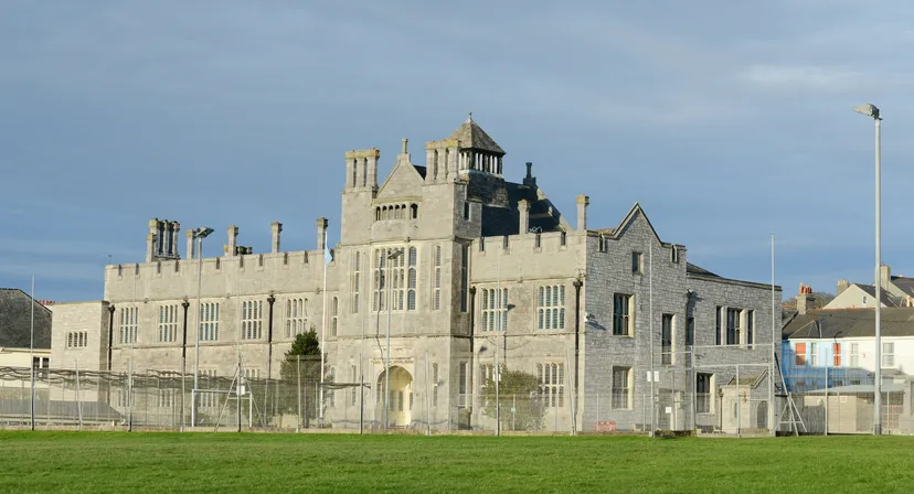 Un castello in stile medievale con torri sorge nel campus del Plymouth College di fronte a un prato.