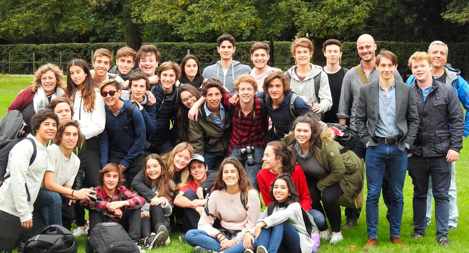 Un gruppo di studenti del Carfax College si riunisce all'aperto davanti ad alberi e aree verdi.