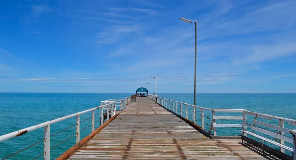 Un pontile in legno si estende sul mare calmo e turchese sotto un cielo limpido nel campus della Seaton High School.