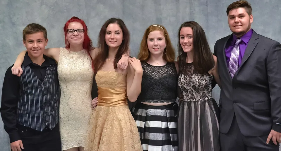 Sei persone in abbigliamento formale posano insieme davanti a uno sfondo grigio in una foto della Erie First Christian Academy.