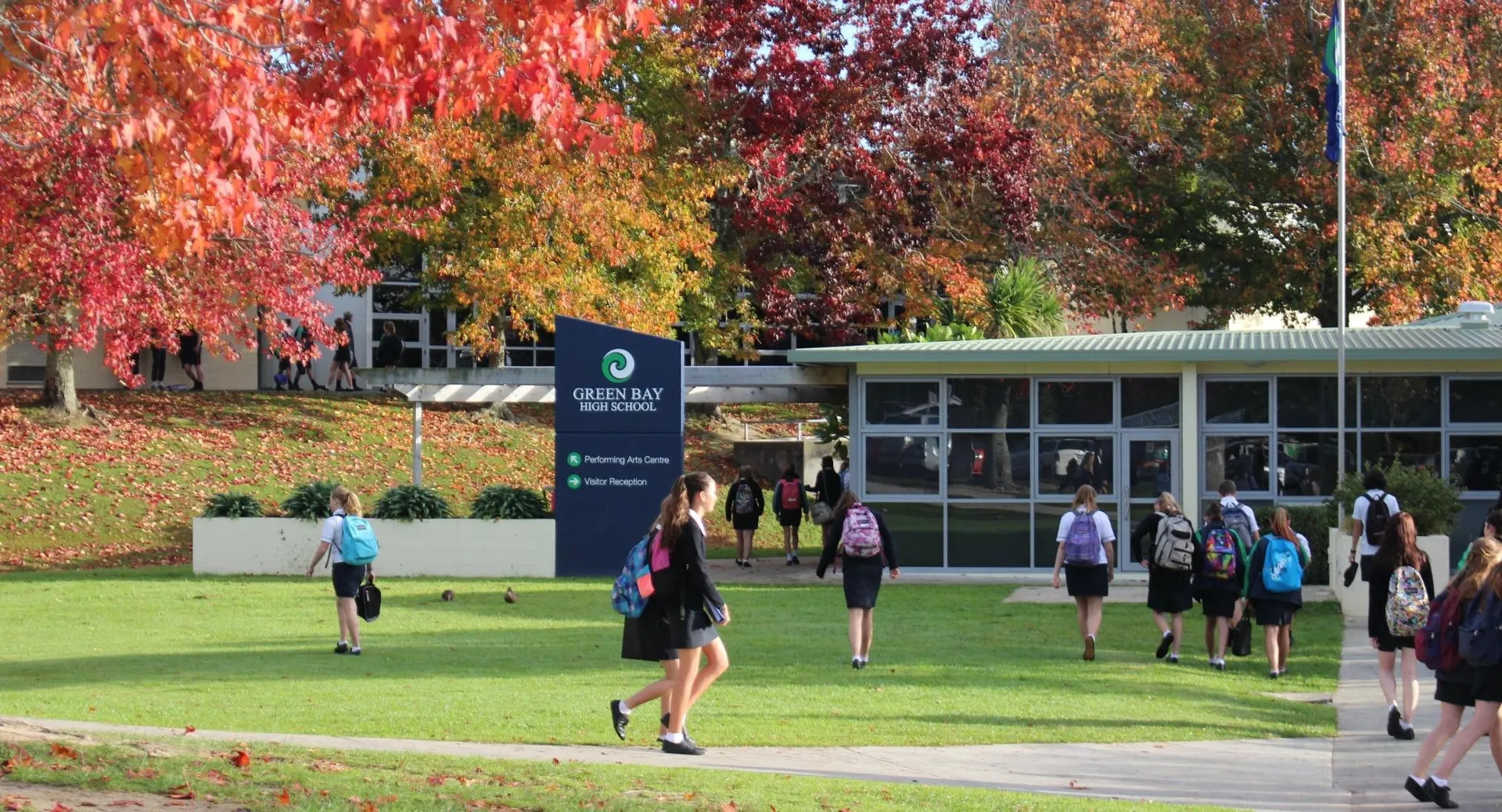 Studenti della Green Bay High School corrono e si radunano nel campus tra alberi dai colori autunnali.