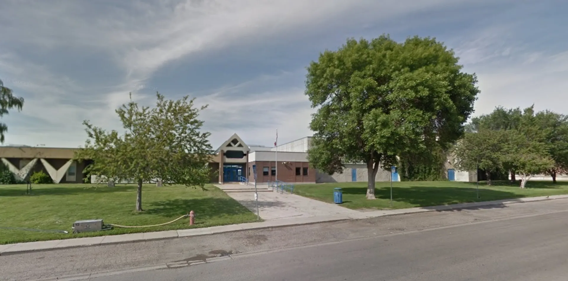 L'edificio colorato con tetto triangolare nel campus della Winston Churchill High School è circondato da alberi e da un'area verde.