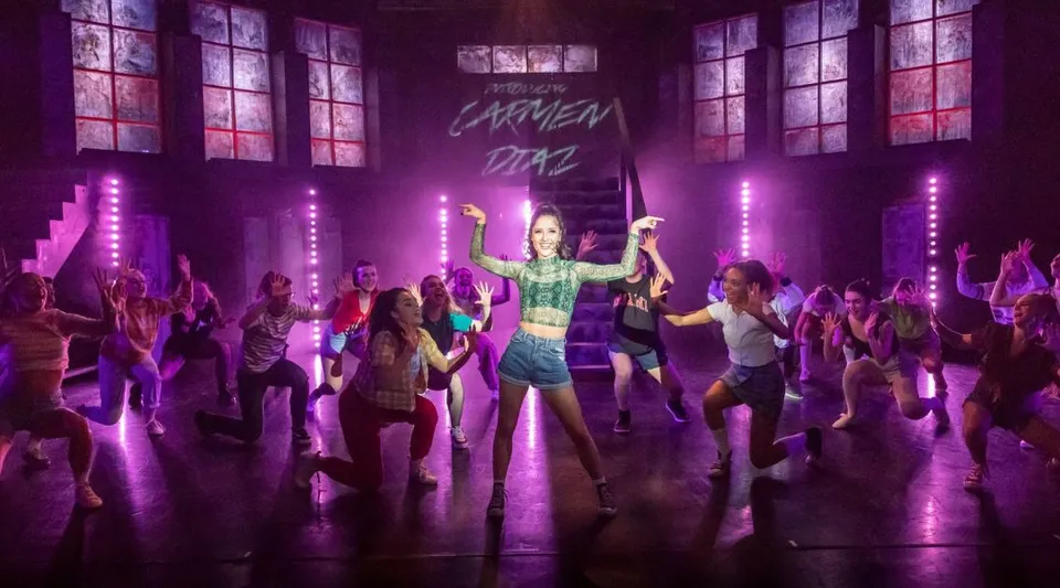 Uno spettacolo di danza sul palco della The Hammond School con ballerini vivaci e luci di scena viola.