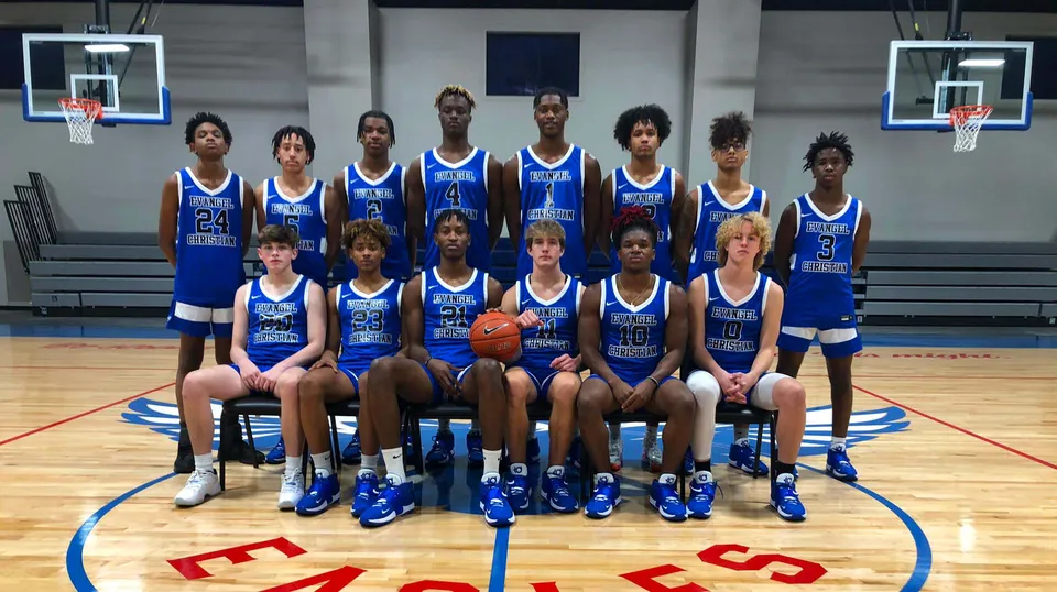 Un gruppo di studenti e studentesse della Evangel Christian Academy posa insieme sul campo da basket con i canestri sullo sfondo.