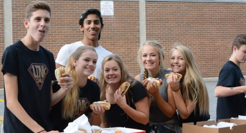 Un gruppo di studenti sta insieme davanti a un edificio in mattoni nel campus della Sir Frederick Banting Secondary School.