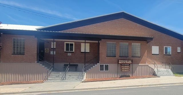 L'edificio in mattoni a due piani della Huntington High School con tetto a falde e scalinata d'ingresso lungo una strada con cavi elettrici.