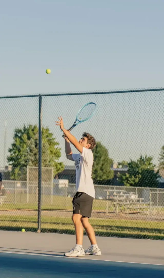 Studente al servizio durante una partita di tennis su un campo negli Stati Uniti