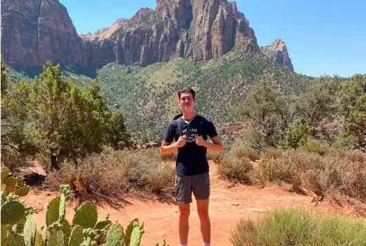 Un ragazzo in piedi davanti a un paesaggio di montagne rocciose e deserto negli Stati Uniti.