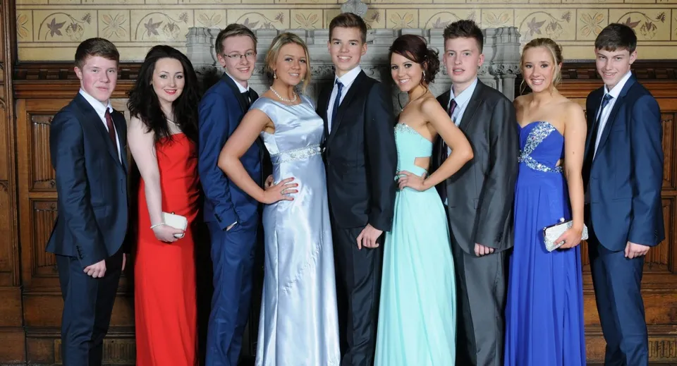 Un gruppo di persone vestite in modo elegante posa davanti all'architettura decorata nel campus del Llandovery College.