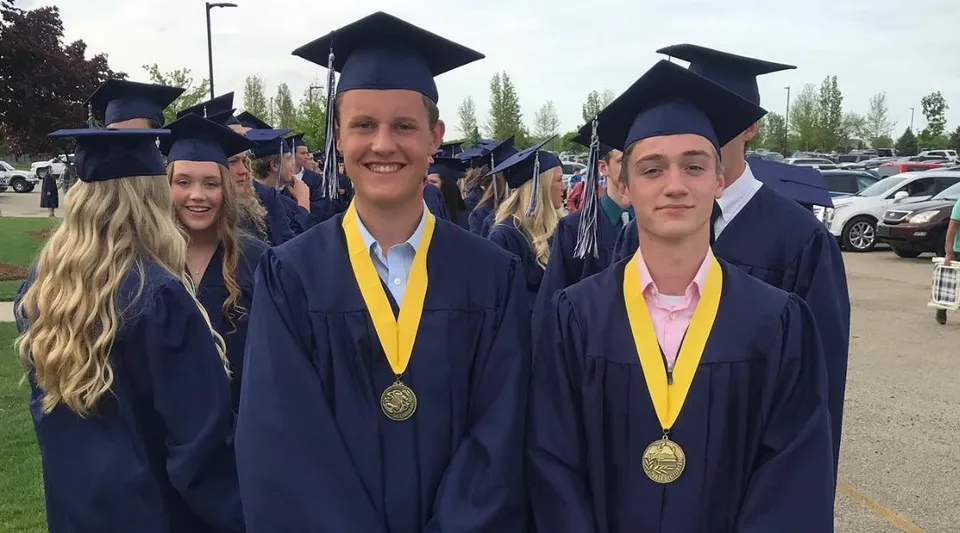 I diplomati e le diplomate della South Christian High School stanno insieme all'aperto e mostrano i loro diplomi.