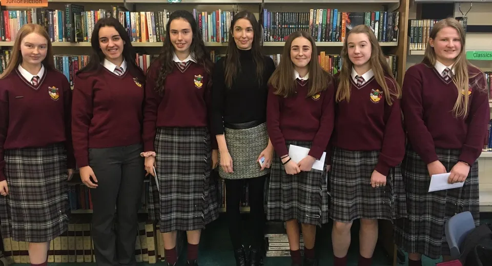Un gruppo di studentesse della Scoil Dara davanti a uno scaffale pieno di libri.